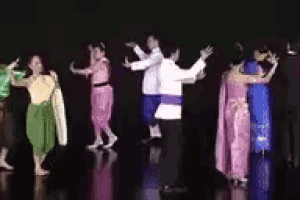 a group of people are dancing together on a stage in a dark room .
