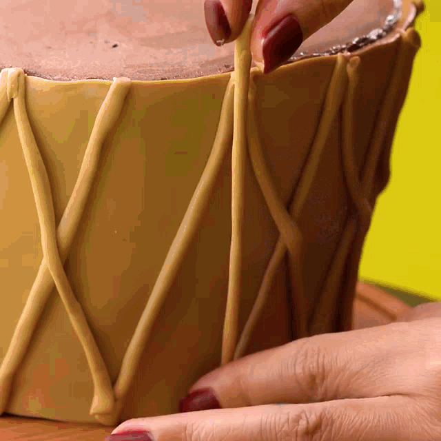 a person with red nails is holding a piece of brown clay