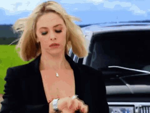 a woman wearing a watch is standing in front of a jeep