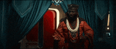 a man in a red robe is standing in front of a blue curtain with the words what the hell written on it