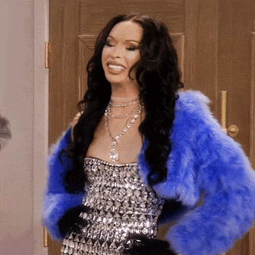 a woman wearing a blue fur jacket and a silver dress