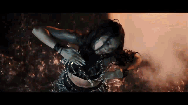 a woman is dancing in front of a fire in a dark room