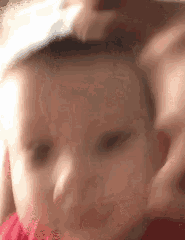 a close up of a baby 's face with a person 's hand on it .