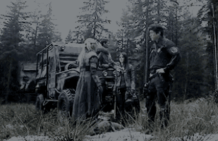 a black and white photo of a group of people standing in the woods