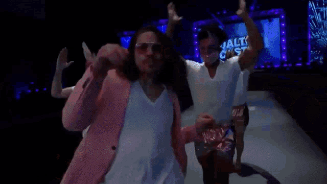 a man in a pink suit is walking down a ramp with other men