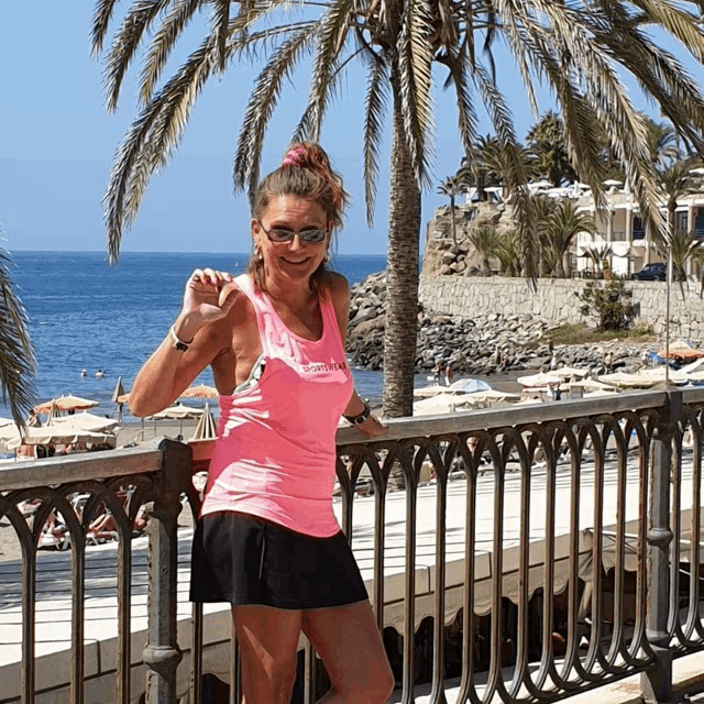 a woman wearing a pink tank top that says ' tropical ' on it