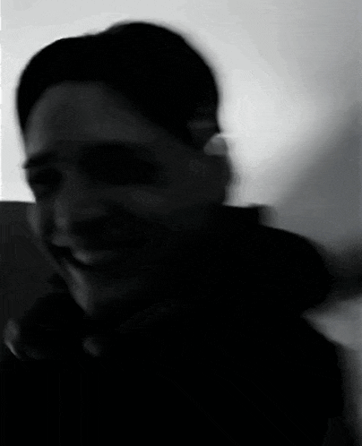 a man in a black jacket is smiling in a black and white photo