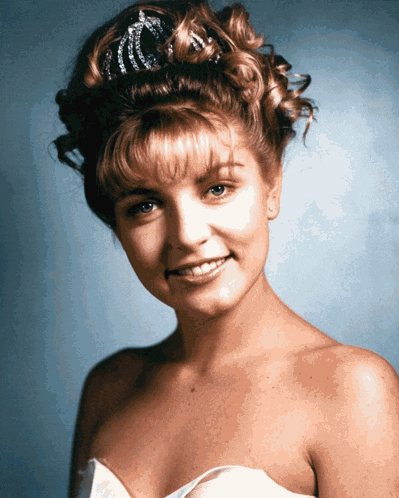 a woman in a white dress with a tiara on her head smiles