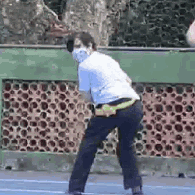 a man wearing a face mask is playing tennis on a court .