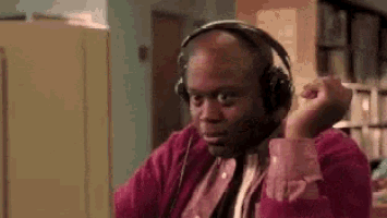 a bald man wearing headphones is sitting in front of a computer screen .