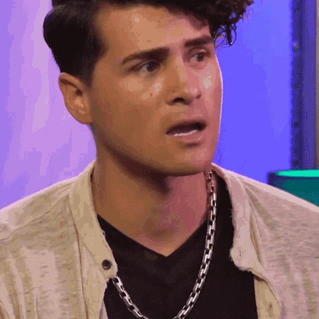 a close up of a man wearing a chain around his neck and a black shirt