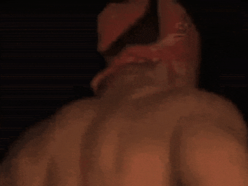 a shirtless man with a red bandana on his head smiles