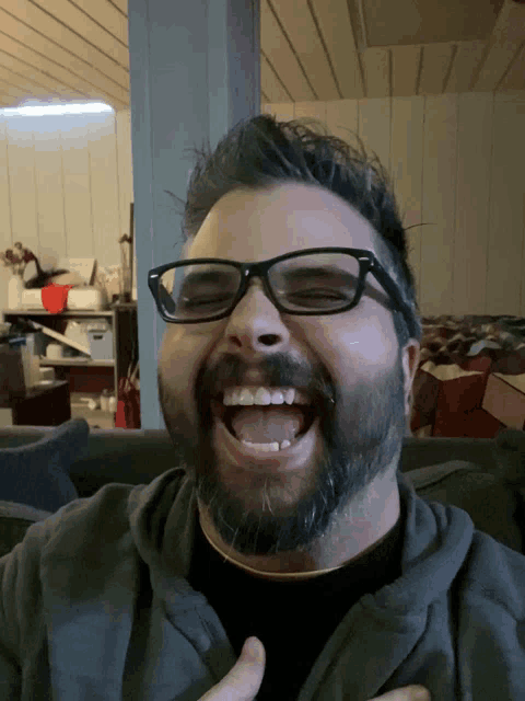 a man with glasses and a beard laughs with his mouth open