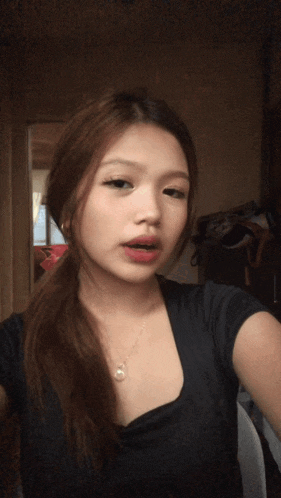 a woman in a black shirt is taking a picture of herself