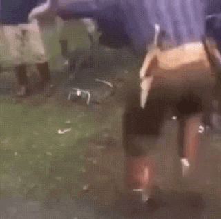a man in a cowboy outfit is doing a handstand in a field .