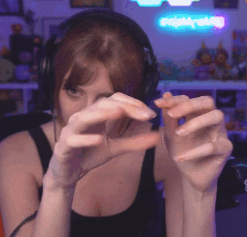 a woman wearing headphones is making a heart with her hands in front of a neon sign that says nightwolf