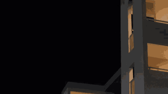 a building is lit up at night with balconies
