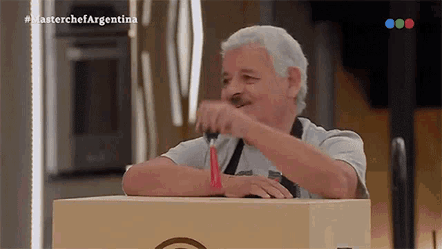 a man is holding a knife in front of a masterchef argentina logo