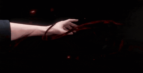 a close up of a person holding another person 's hand with a red light coming out of it .