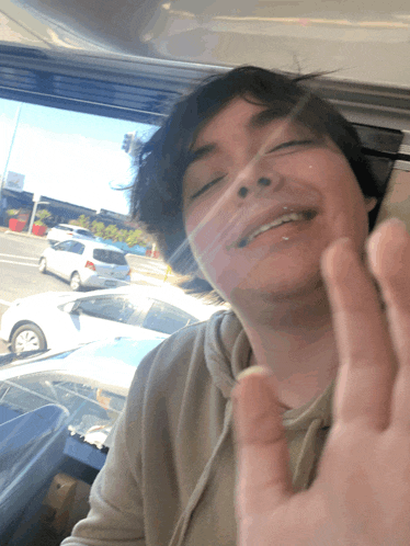 a young man with his eyes closed and his hand up