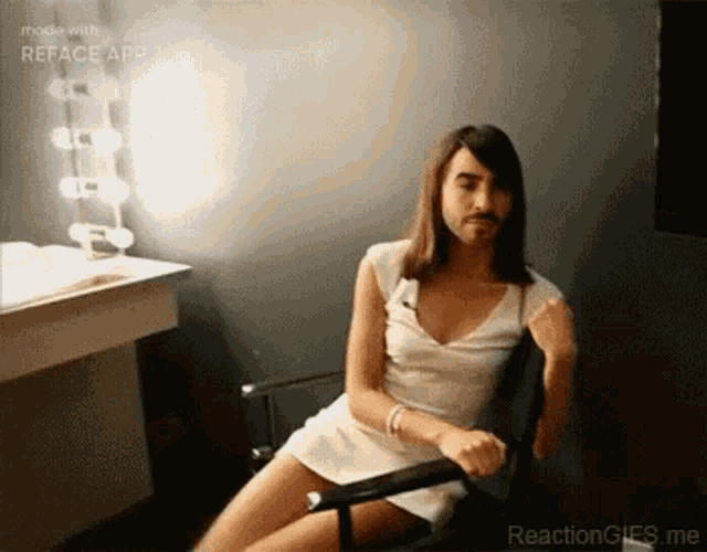 a man with long hair and a beard is sitting in a chair in front of a mirror .
