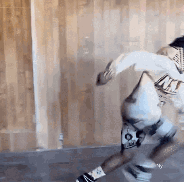 a person is skateboarding in a room with a wooden wall .