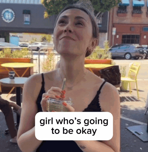 a woman drinking from a cup with a straw and a sign that says girl who 's going to be okay
