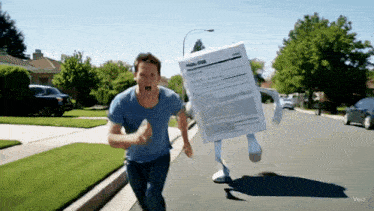 a man in a blue shirt is running down a street with a box on his back that looks like a form