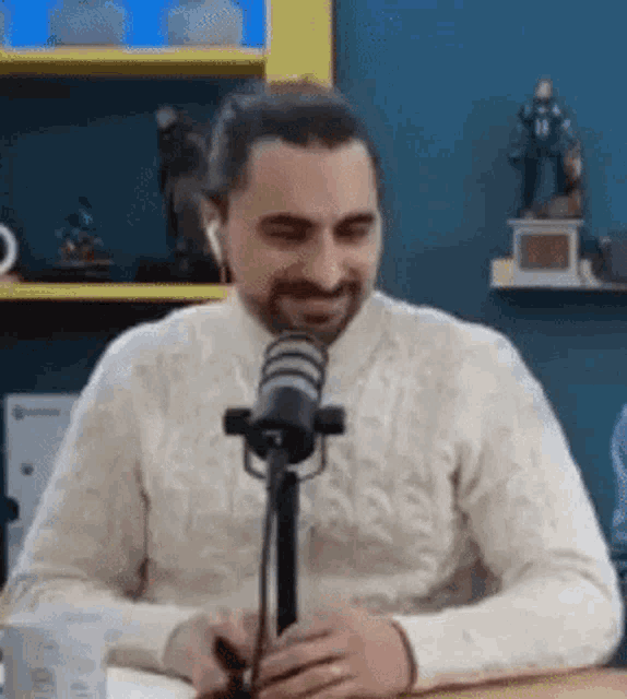 a man is sitting at a table in front of a microphone wearing headphones .
