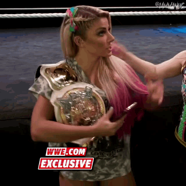 a woman in a wrestling ring holding a wwe.com exclusive belt