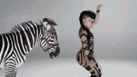 a woman is dancing next to a zebra on a white surface .