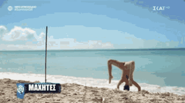 a man doing a handstand on a beach with a sign that says maxhtei