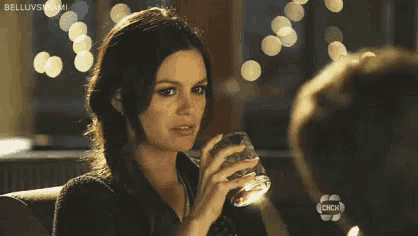 a woman is drinking a glass of whiskey while sitting at a table .