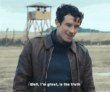 a man wearing a leather jacket and a sweater is smiling and saying well i 'm great is the truth .