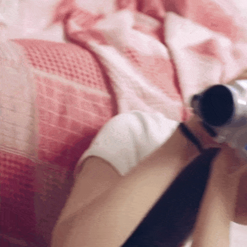 a woman is laying on a bed and holding a camera .