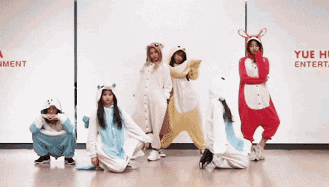 a group of girls in animal costumes are posing for a picture in front of a sign that says yue entertainment