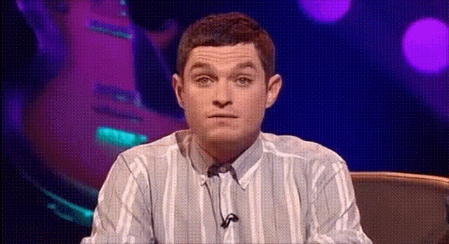 a man in a striped shirt is sitting in front of a microphone and making a funny face