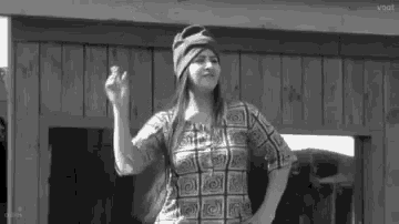 a black and white photo of a woman wearing a hat and a plaid shirt