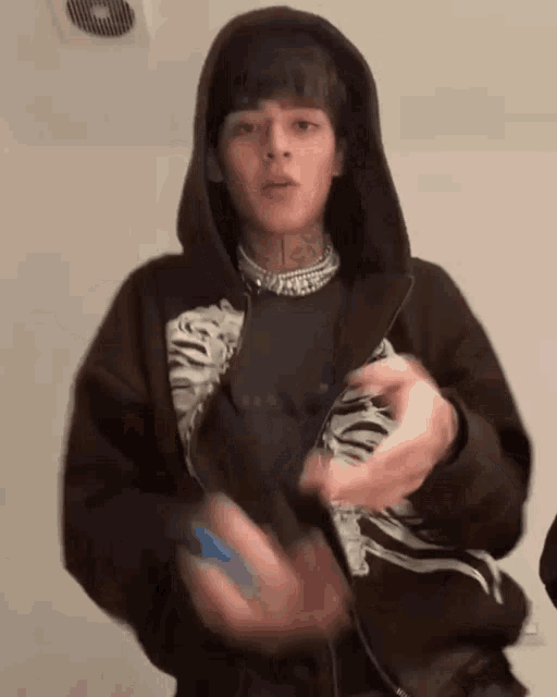 a young man wearing a hoodie and a necklace is holding a lighter .