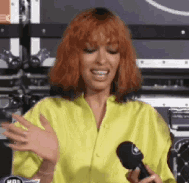 a woman with red hair is holding a microphone in her hand and smiling .