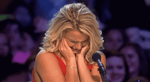 a woman is crying while sitting in front of a microphone in front of a crowd .