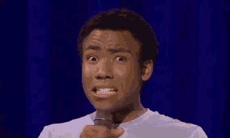 a man is holding a microphone and making a surprised face .