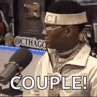 a man wearing a headband and glasses is sitting in front of a microphone and saying `` couple ! ''