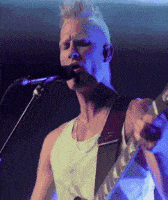 a man is singing into a microphone while holding a guitar