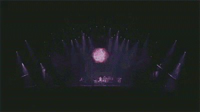a group of people are standing on a stage in front of a purple light .