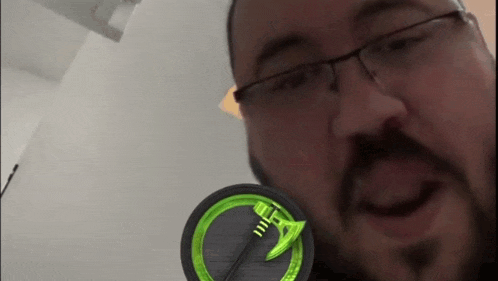 a man wearing glasses and a beard is holding a green object