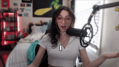 a woman wearing glasses stands in front of a microphone