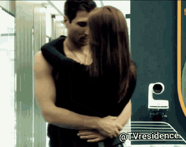 a man and a woman are hugging and kissing in a room with a sign that says tvresidence