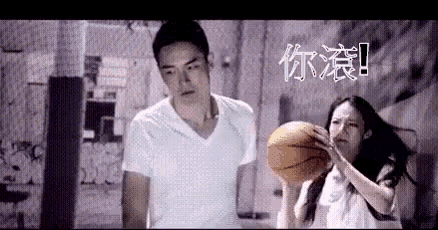a man and a woman are playing basketball in a gym .