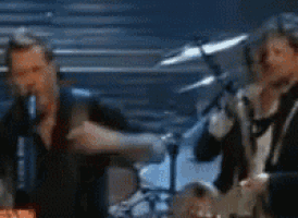 a blurry picture of a group of men playing instruments on a stage .